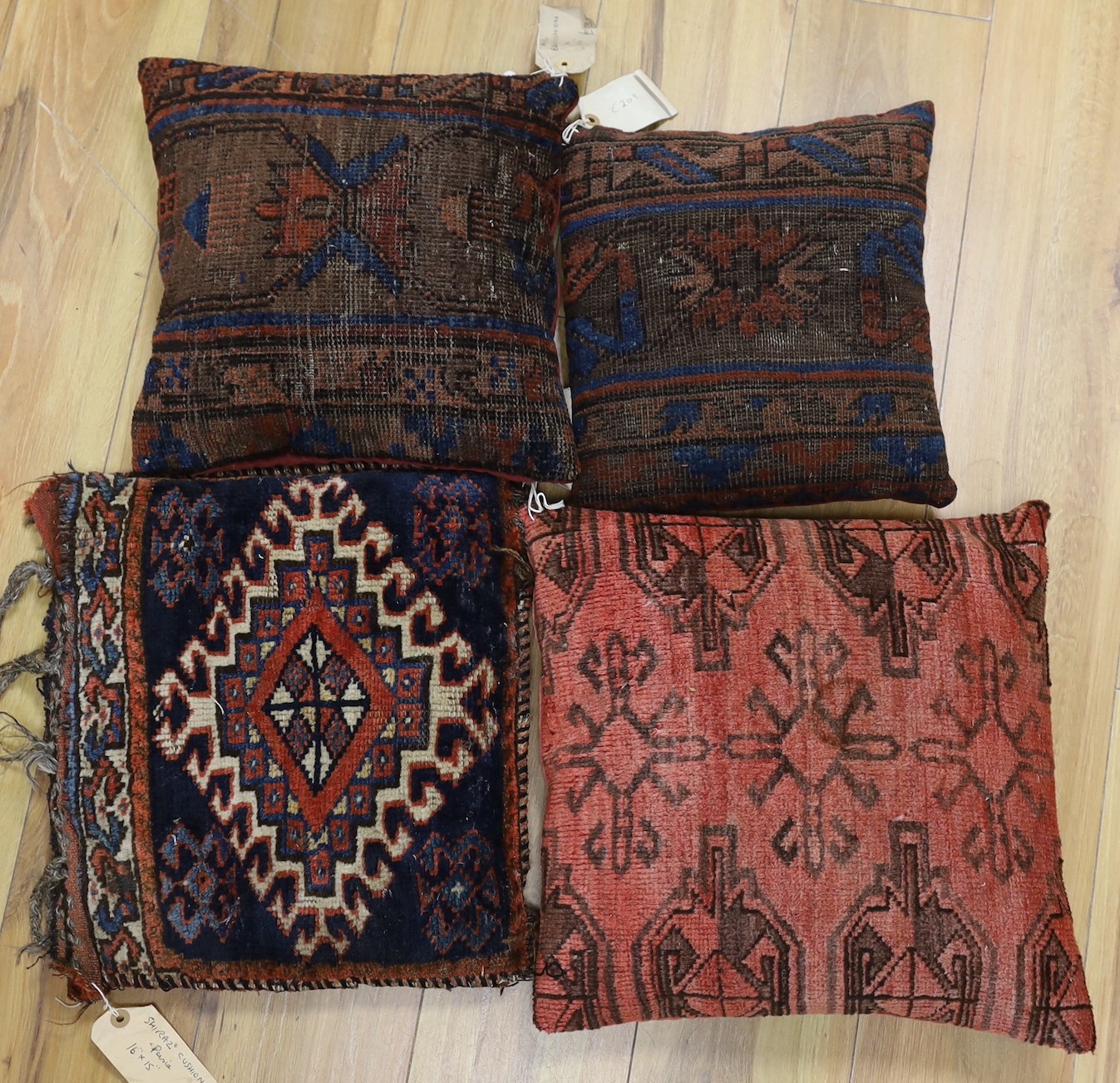 A pair of antique Persian belouch cushions, together with an Afghani Chubbash cushion, 16